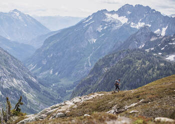 A male hiker walks on a trail with a view in the Cascades, Washington - CAVF68539