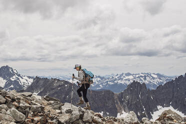 A female hiker walks amid the snowy peaks of the Cascades, Washington - CAVF68540