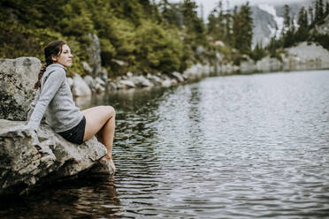 Eine Wanderin taucht ihre Zehen in den Snow Lake, Snoqualmie Pass, Washington - CAVF68550