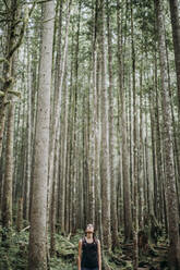 Eine Wanderin blickt auf die Bäume in einem Wald in Washington - CAVF68556