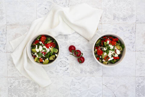 Salatschüsseln mit Beluga-Linsen, Tomaten, Paprika, Zucchini, Feta-Käse, Minze und Petersilie, lizenzfreies Stockfoto