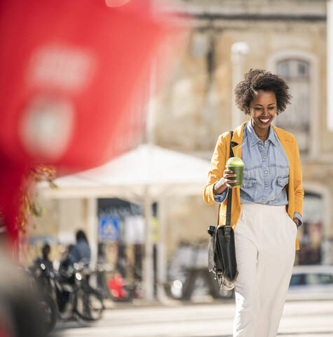 Smiling young woman in the city on the go stock photo