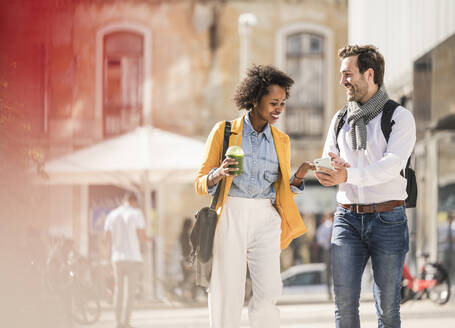 Happy young couple looking at smartphone in the city - UUF19569