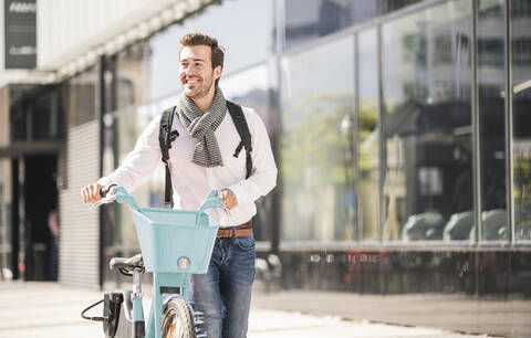 Smiling young man with bicycle in the city on the go stock photo