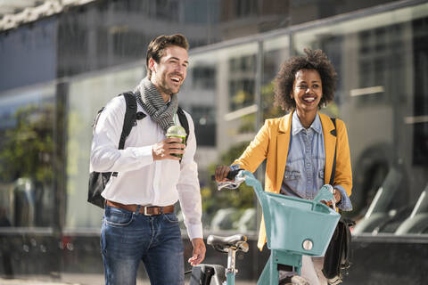 Glücklicher junger Mann und Frau mit Fahrrad in der Stadt unterwegs, lizenzfreies Stockfoto