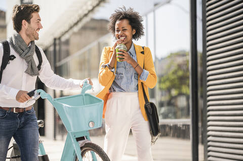 Glücklicher junger Mann und Frau mit Fahrrad in der Stadt unterwegs, lizenzfreies Stockfoto