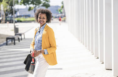 Portrait of smiling young woman in the city - UUF19611