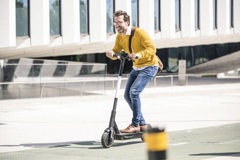 Young man riding e-scooter in the city - UUF19629