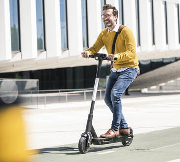 Young man riding e-scooter in the city - UUF19630