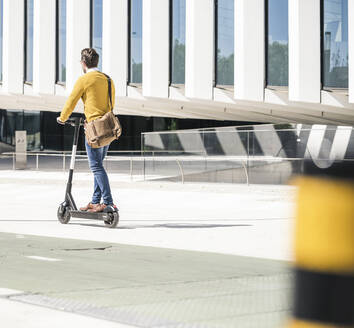 Young man riding e-scooter in the city - UUF19632