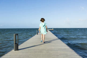 5 year old boy walking on a pier, view to the horizon - MINF12973