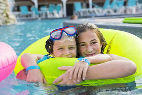 Geschwister, Bruder und Schwester spielen im Pool mit bunten Schwimmflügeln. - MINF12984