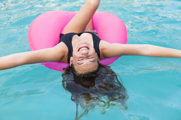Lächelndes Teenager-Mädchen in buntem Schwimmanzug in einem Schwimmbad - MINF12993