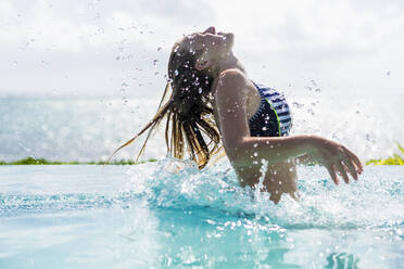 Ein junges Mädchen im Infinity-Pool, das sein Haar zurückwirft - MINF13003