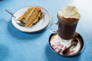Nahaufnahme eines Stücks Kuchen und heißer Schokolade auf blauem Hintergrund. - MINF13029