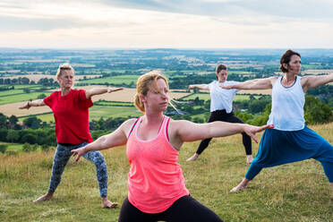 Eine Gruppe von Frauen nimmt an einer Yogastunde auf einem Hügel teil. - MINF13077