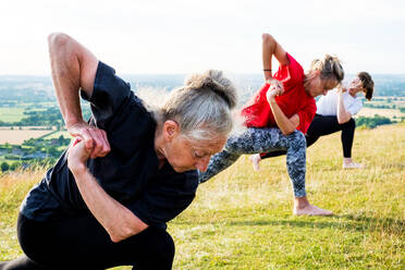 Eine Gruppe von Frauen nimmt an einer Yogastunde auf einem Hügel teil. - MINF13087