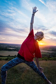 Ältere Frau, die an einer Yogastunde auf einem Berghang teilnimmt. - MINF13091