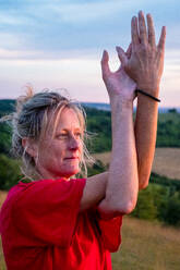 Mature woman taking part in a yoga class on a hillside. - MINF13093