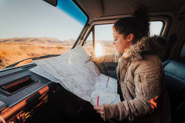 Young woman looking at a map during a Californian road trip - CAVF68580
