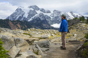 Male Hiking In The Alpine With Glacier Covered Mountain - CAVF68586