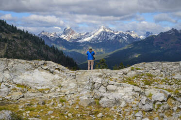 Männlicher Wanderer, der über einem Tal mit Bergblick steht - CAVF68588