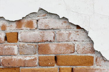 A brick wall and plasterwork flaking off. - MINF13108