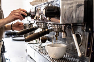 Nahaufnahme einer Person, die mit einer kommerziellen Espressomaschine einen Cappuccino zubereitet. - MINF13163