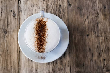 Eine Tasse Kaffee in einem Café, ein Cappuccino mit Schaumkrone und Schokoladenpulver bestreut. - MINF13201