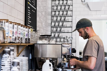 Ein männlicher Barista arbeitet an einer Kaffeemaschine in einem Café. - MINF13204