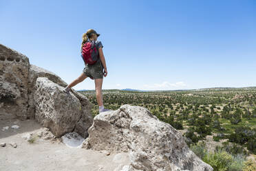 Rear view of teenage girl hiker overlooking desert vista at the Tsankawi Ruins - MINF13238