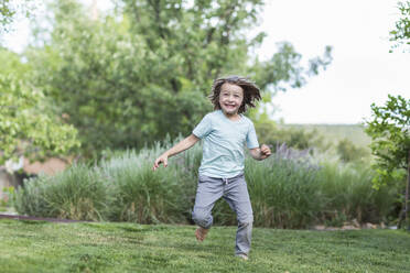 5 year old boy running on green lawn - MINF13255