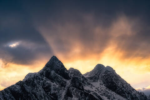 Norwegischer Sonnenuntergang, der die dicken Wolken des Winters durchdringt, lizenzfreies Stockfoto