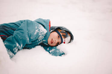 Nachdenklicher Junge im Schnee liegend im Winter - CAVF68778