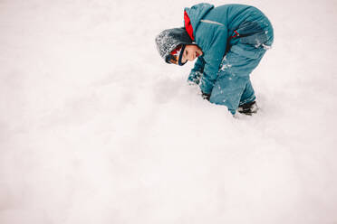 Glücklicher Junge spielt mit Schnee im Winter - CAVF68780