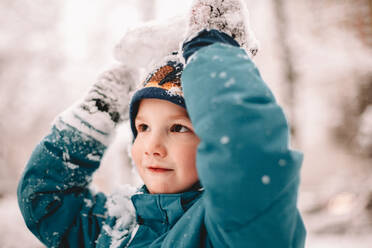 Glücklicher Junge spielt mit Schnee im Winter - CAVF68782