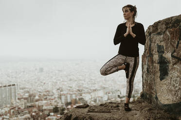 Junge Frau übt Yoga, Asana mit Blick auf die Stadt - CAVF68813