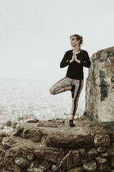 Young woman practicing yoga, asana looking at the city - CAVF68814