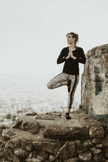 Junge Frau übt Yoga, Asana mit Blick auf die Stadt - CAVF68814