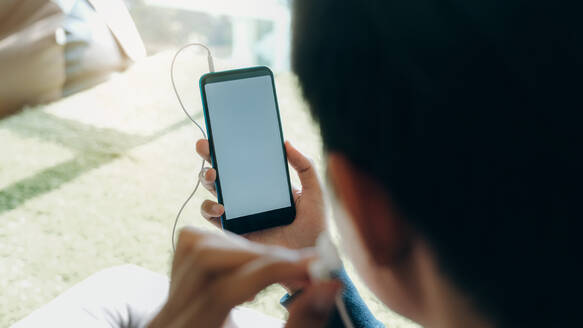 Junger Mann entspannt sich und hört Musik vom Handy. - CAVF68893