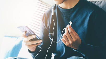 Junger Mann entspannt sich und hört Musik vom Handy. - CAVF68896