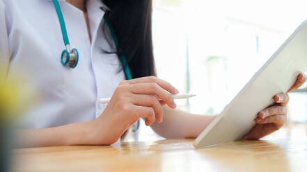 Close up doctor examining medical report while using computer ta - CAVF68906