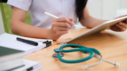 Close up doctor examining medical report while using computer ta - CAVF68907