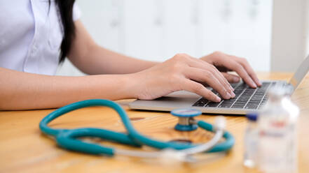 Close up doctor examining medical report while using computer ta - CAVF68908