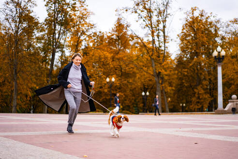 Frau läuft im Park mit einem Cavalier King Charles Spaniel Hund - CAVF68922