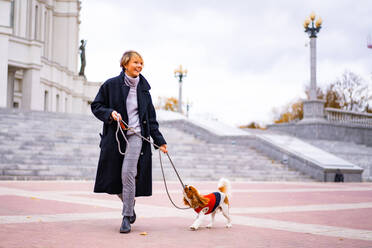 Frau spielt mit einem Cavalier King Charles Spaniel im Freien. - CAVF68925