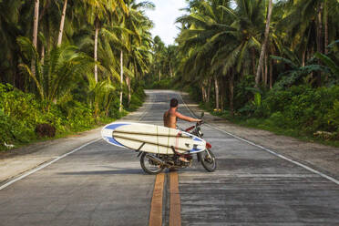 Mann fährt Motorrad mit Surfbrettern in Kokosnuss Straße Palmen philippinischen - CAVF68933