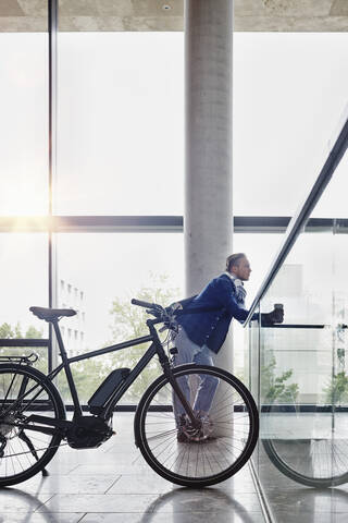 Student mit Coffee to go und E-Bike an der Goethe-Universität, lizenzfreies Stockfoto