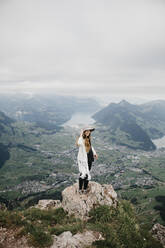 Young woman wearing hat, standing on viewpoint, Grosser Mythen, Switzerland - LHPF01138