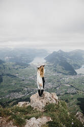 Young woman wearing hat, standing on viewpoint, Grosser Mythen, Switzerland - LHPF01139